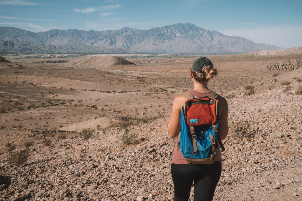 a women standing on the edge of a cliff looking at mountains