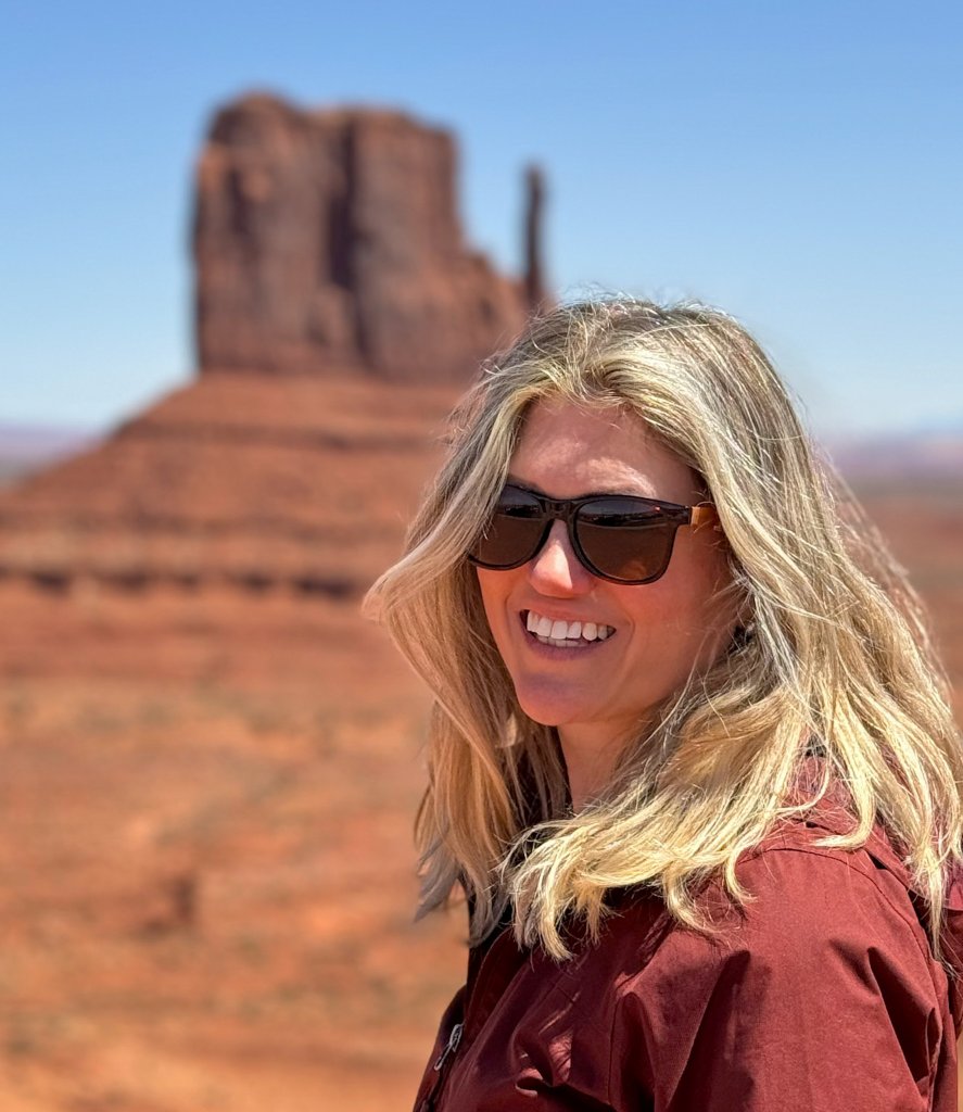 a woman standing next to monument valley