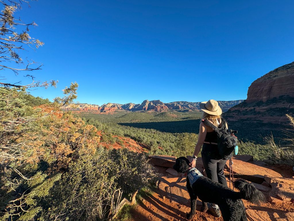 a women and a black dog standing in the red rocks of the desert in Sedona, AZ