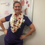 a woman standing in a hospital with a bunch of leis