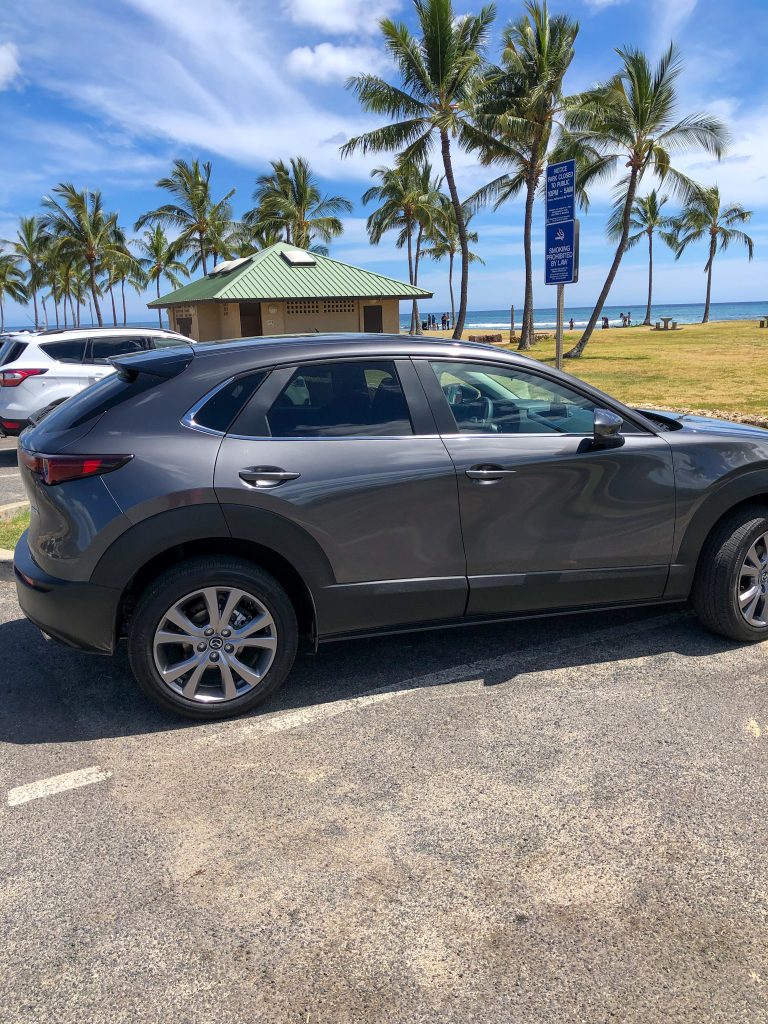 a picture of a gray Mazda on a beach in Hawaii