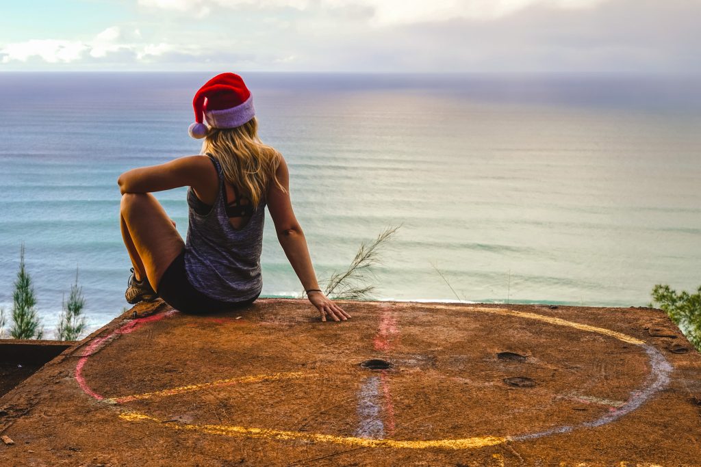 a women sitting in a santa hat looking at the ocean