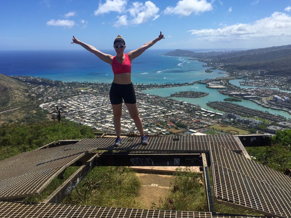 a woman standing on a ledge next to the ocean