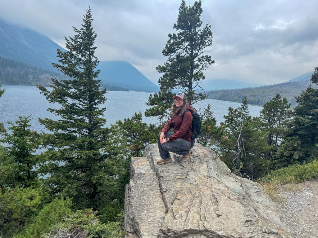 a woman sitting on a rock by a lake