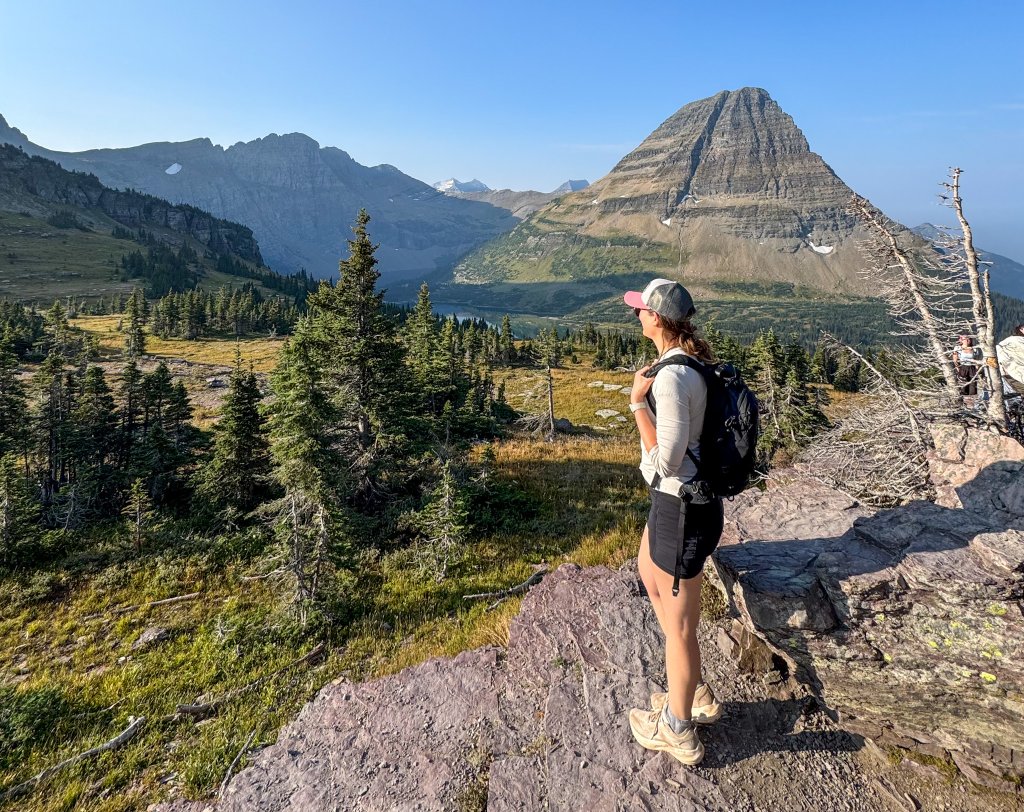a women standing at the edge of a cliff looking at a lake