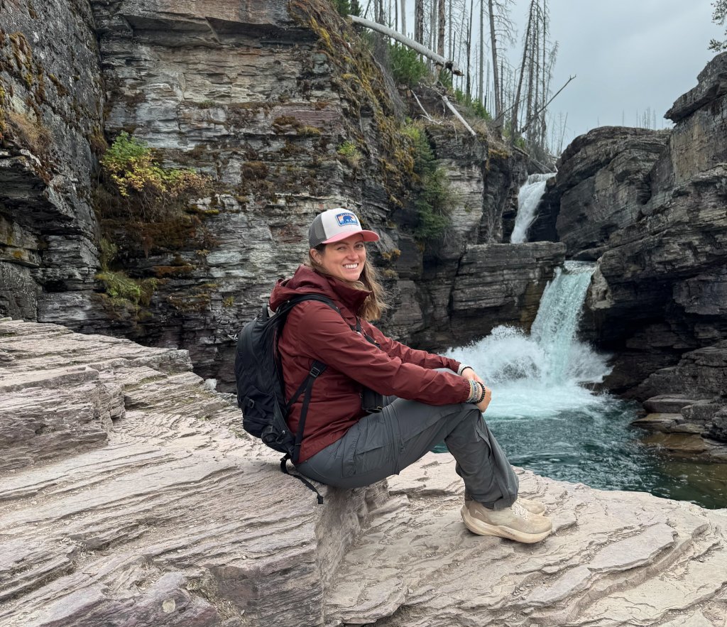 a woman sitting in front of st. mary falls