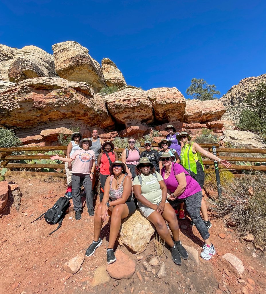 a group of people standing next to red rocks