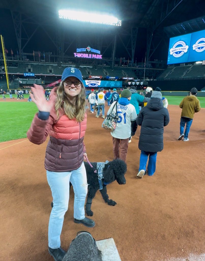 a woman and a dog standing on a baseball field