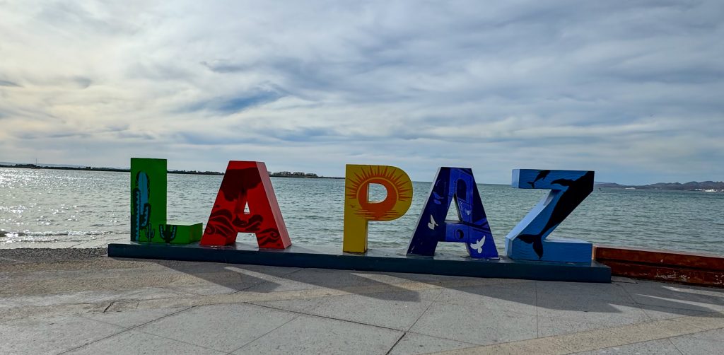 a sign that says La Paz next to the ocean